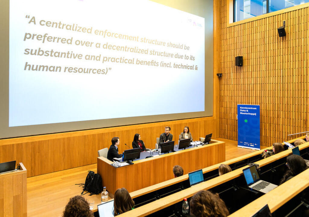 Mannen en vrouwen in een paneldiscussie. De setting is professioneel. 
Men and women in a panel discussion. The setting is professional.
