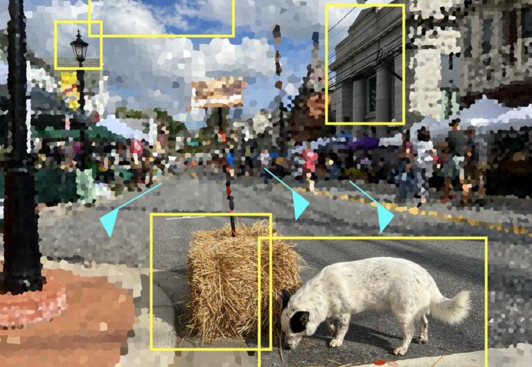 The image shows a pixelated image of a street. While it is heavily pixelated, you can make out lamposts, people walking on the sidewalks, and stalls/buildings that line wach side of the road. In the forefront, there is a stack of hay and a dog which is sniffing it. There are various yellow boxes outlining different parts of the image including: the light of a lamp post, the dog, a hay stack, and an old-style building.