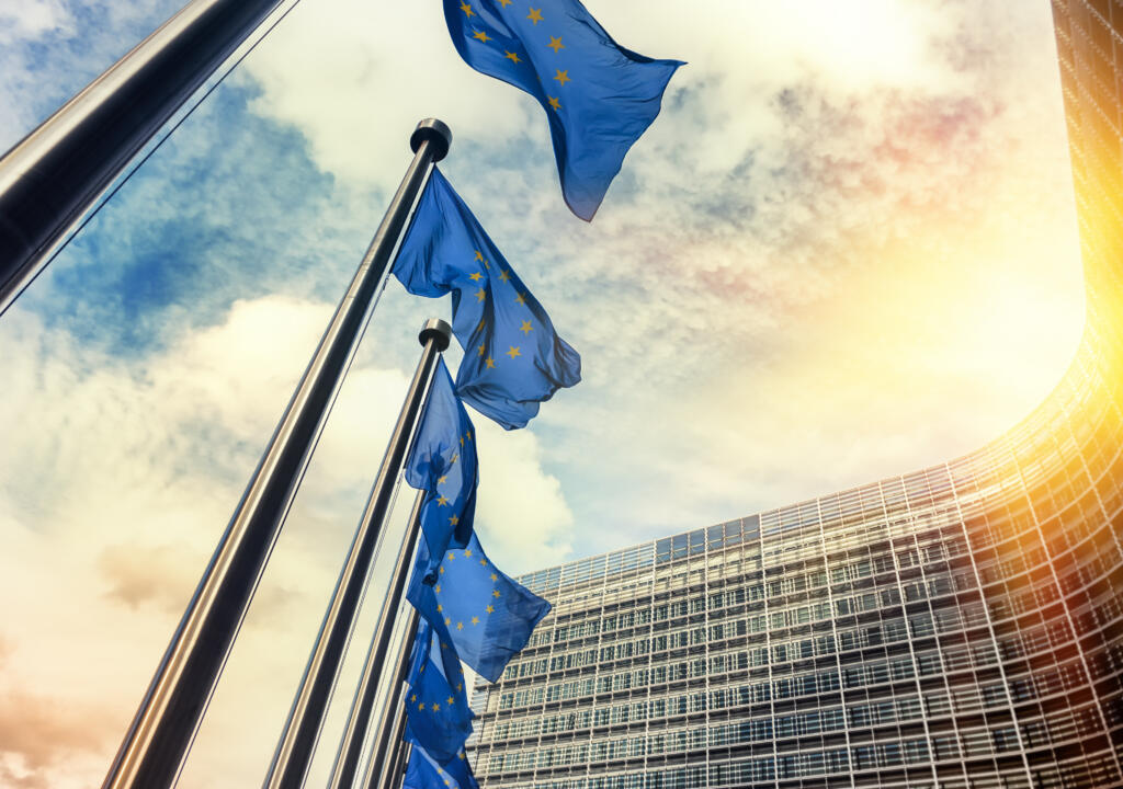 Waving EU flags in front of European Commission in Brussels at sunset