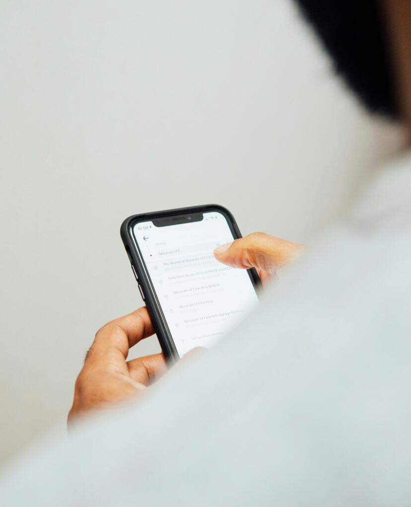 person photographed from the back. The photo shows a person scrolling on the phone.
